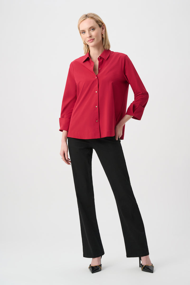 Woman wearing a red blouse and black pants on a white background