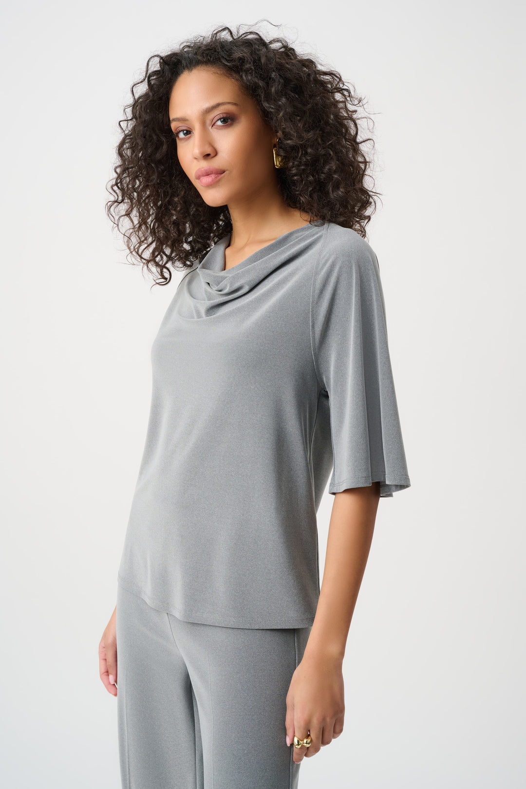 Woman wearing a gray outfit with a cowl neckline on a white background