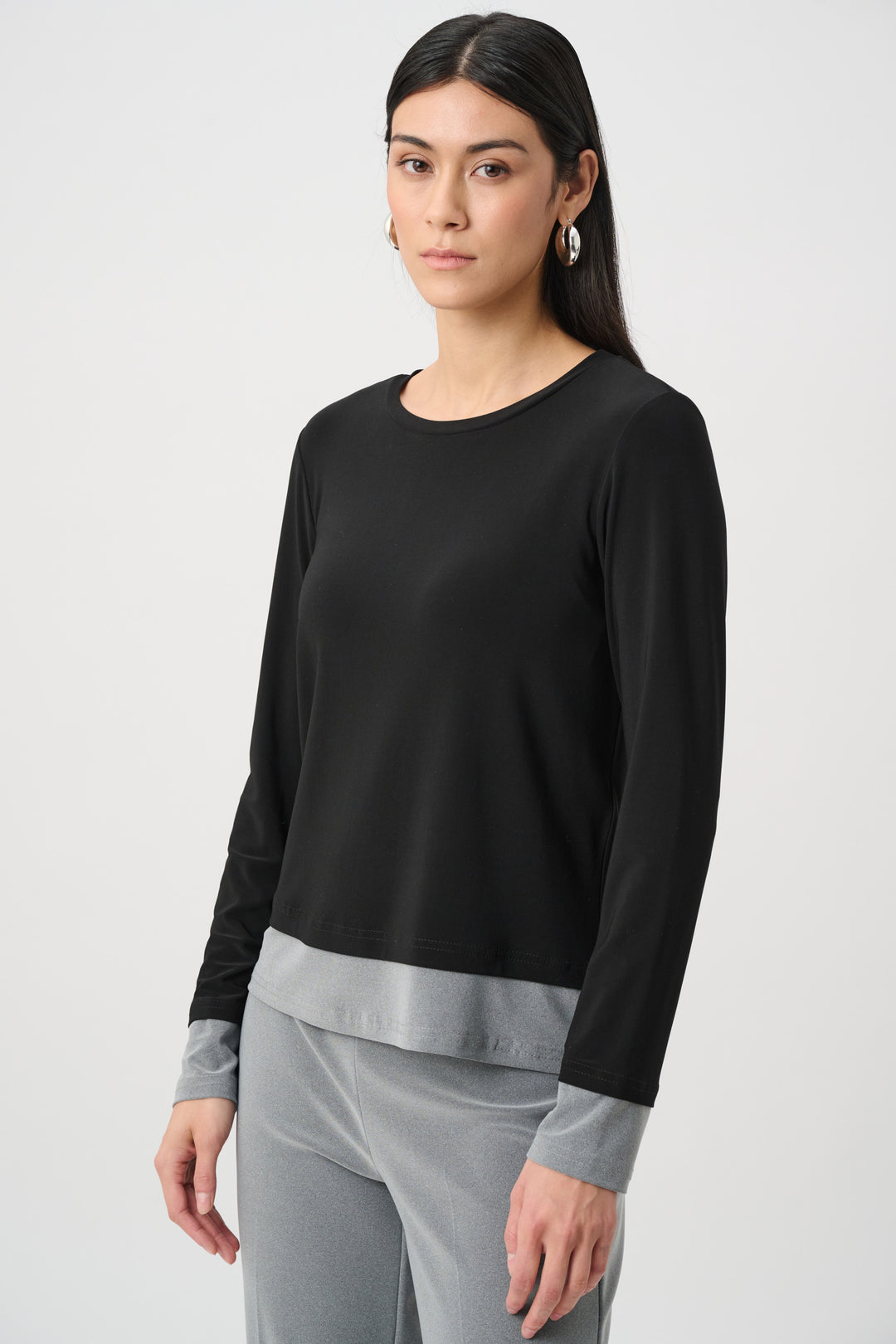 Woman wearing a black long-sleeve top with gray cuffs and hem on a white background