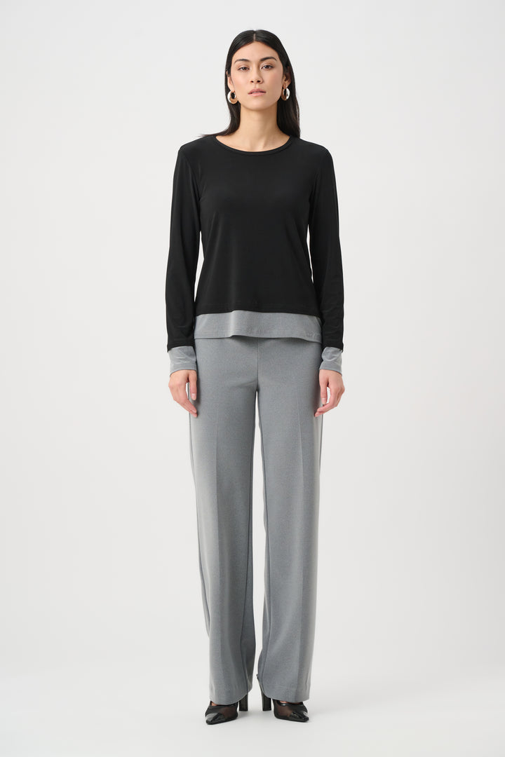 Woman wearing a black long-sleeve top and gray pants on a white background