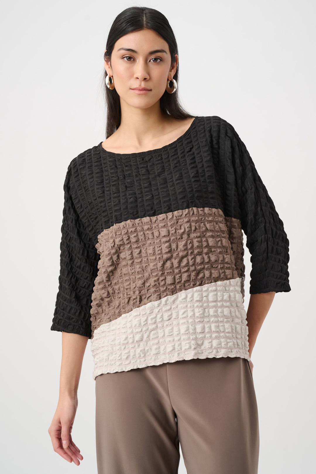 Woman wearing a black, brown, and beige textured sweater on a white background