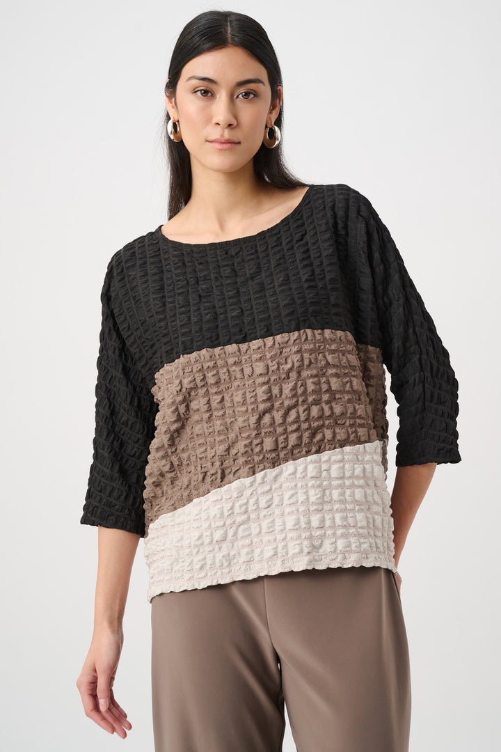 Woman wearing a black, brown, and beige textured sweater on a white background