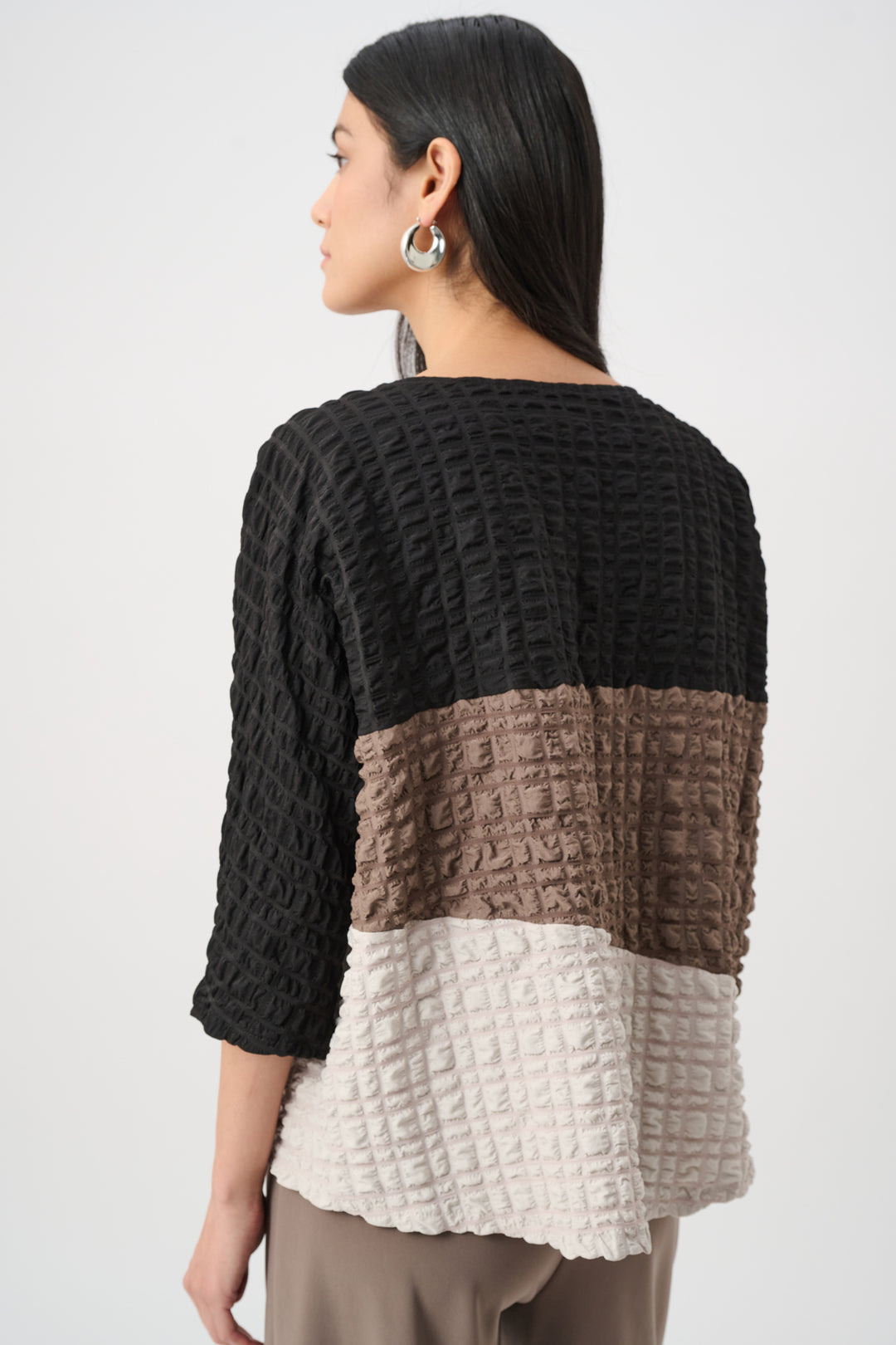 Woman wearing a black, brown, and beige layered sweater on a white background