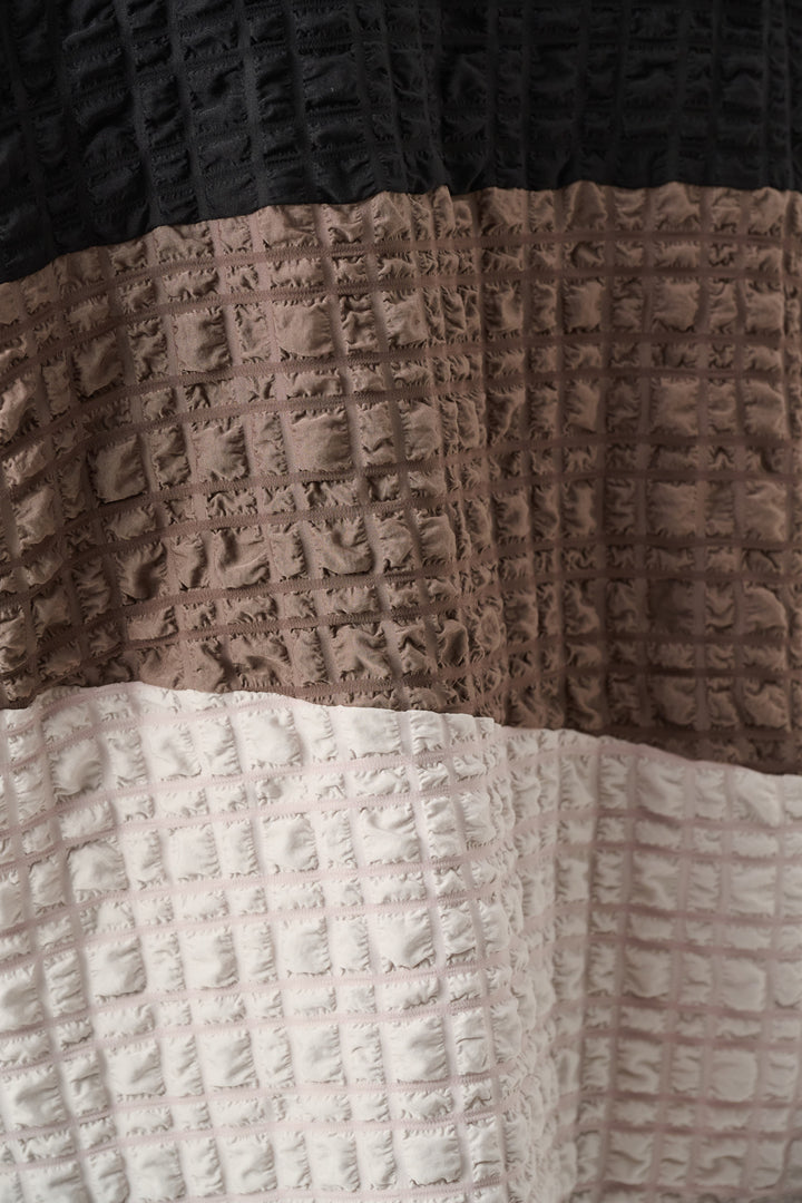 Textured fabric with waffle pattern in brown, beige, and black.
