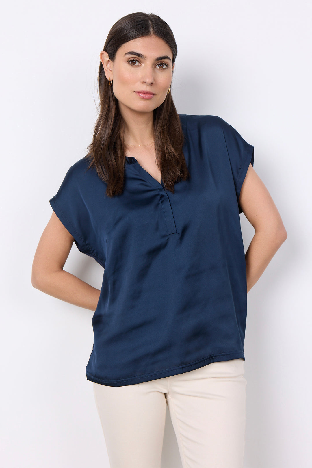 woman wearing a silk t-shirt blouse and jeans on a white background. 