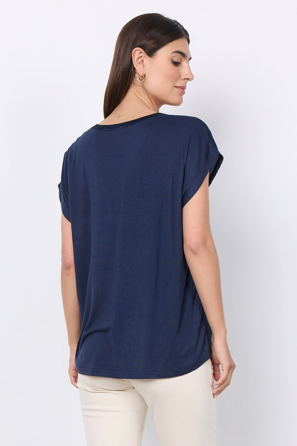woman wearing a silk t-shirt blouse and jeans on a white background. 