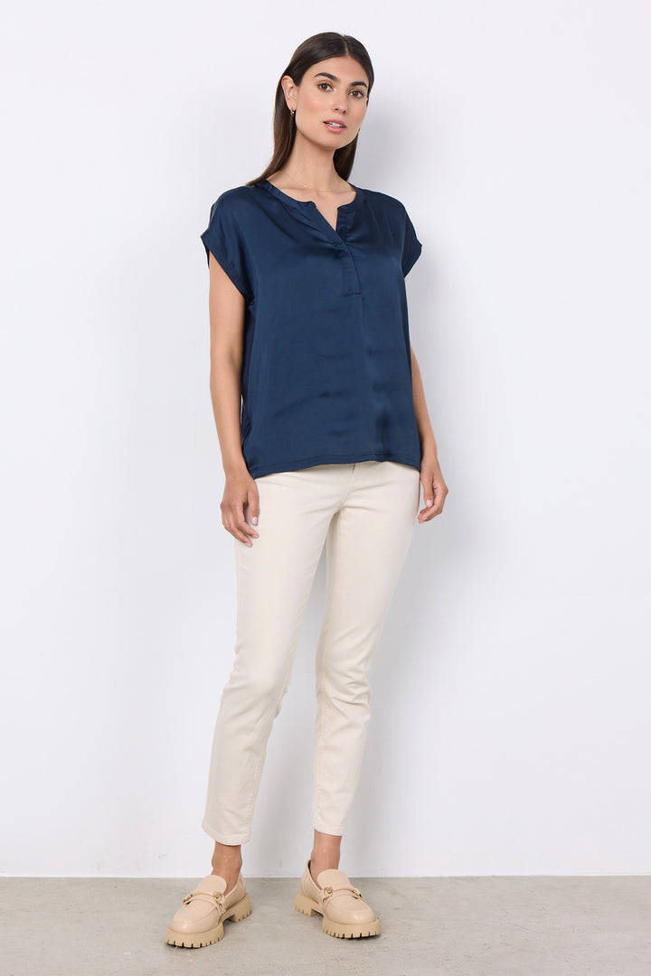 woman wearing a silk t-shirt blouse and jeans on a white background. 
