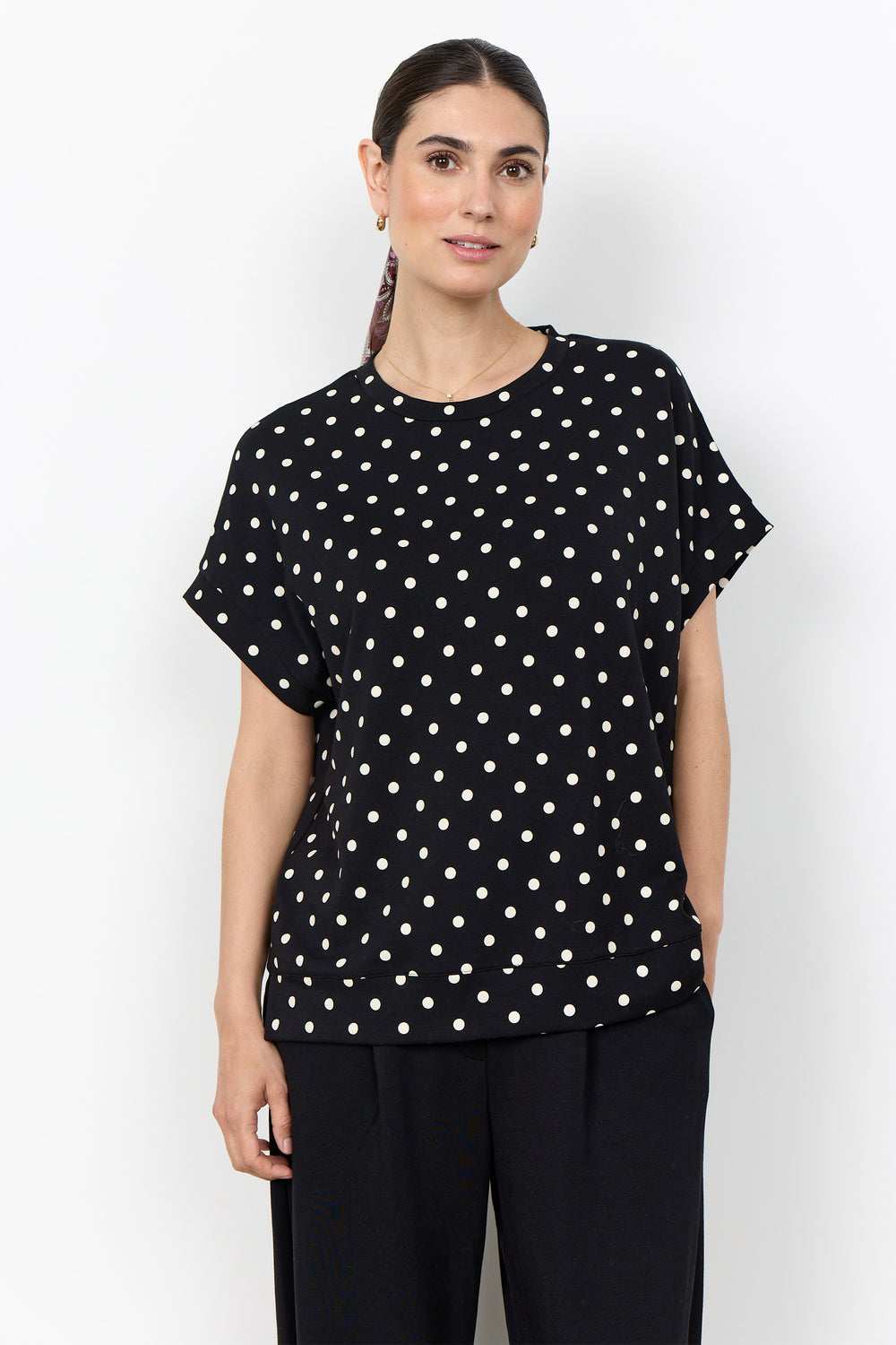 woman wearing a polka t-shirt blouse on a white background. 