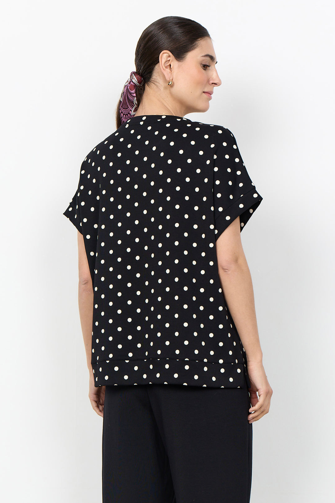 woman wearing a polka t-shirt blouse on a white background. 