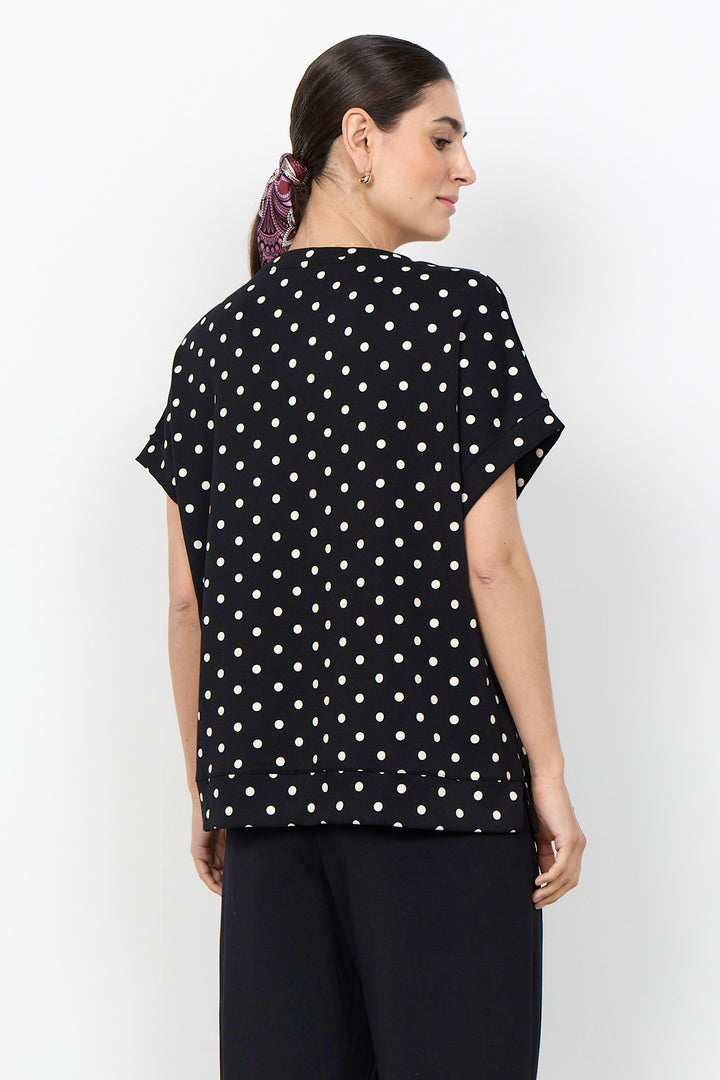 woman wearing a polka t-shirt blouse on a white background. 