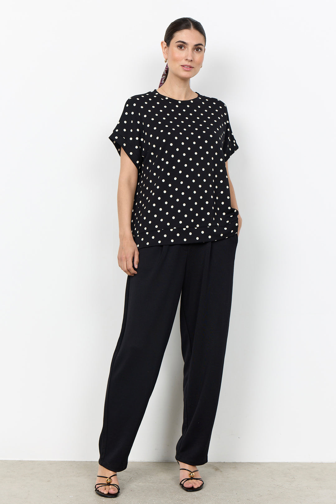 woman wearing a polka t-shirt blouse on a white background. 