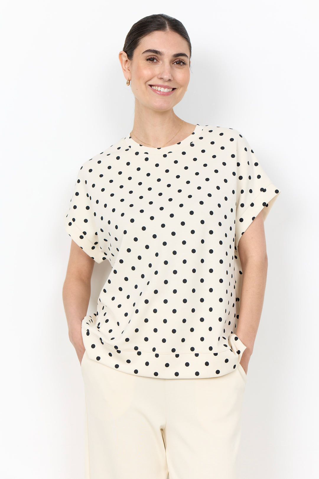 woman wearing a polka t-shirt blouse on a white background. 