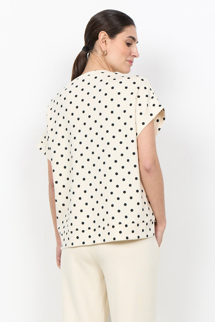 woman wearing a polka t-shirt blouse on a white background. 