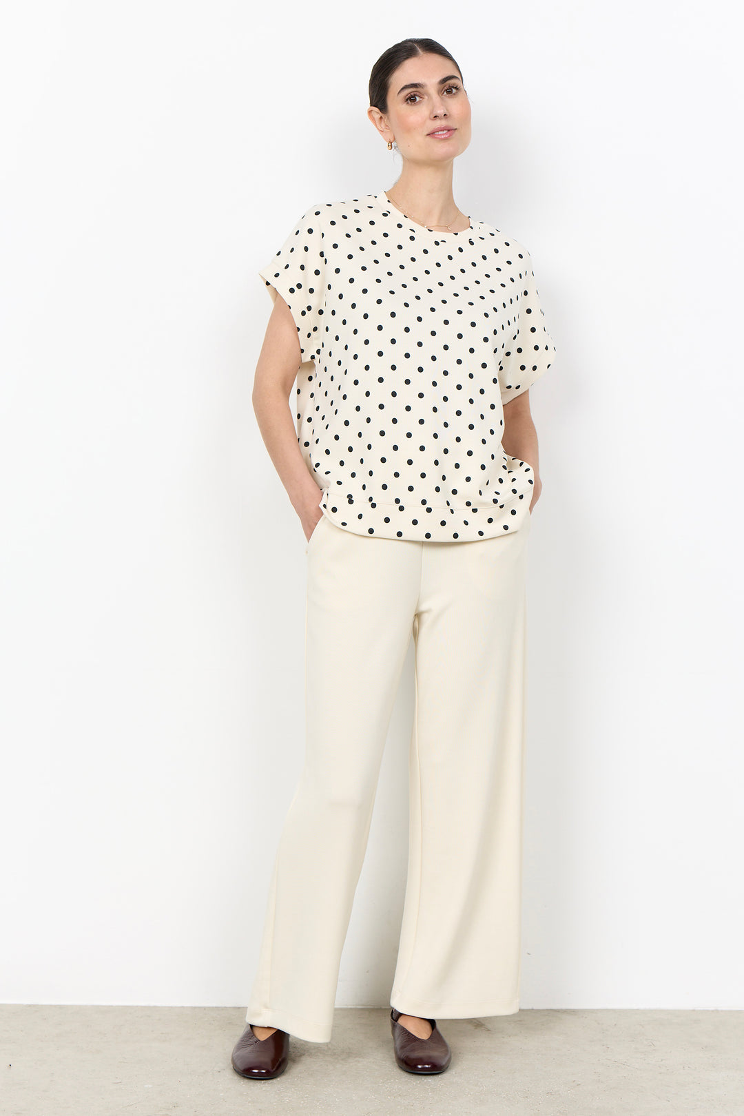 woman wearing a polka t-shirt blouse on a white background. 