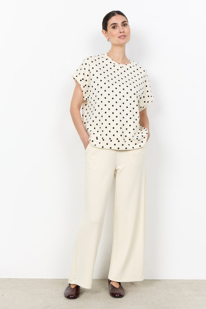 woman wearing a polka t-shirt blouse on a white background. 