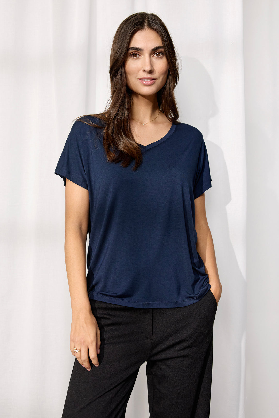 woman wearing a casual basic t-shirt  and black pants on a white background. 