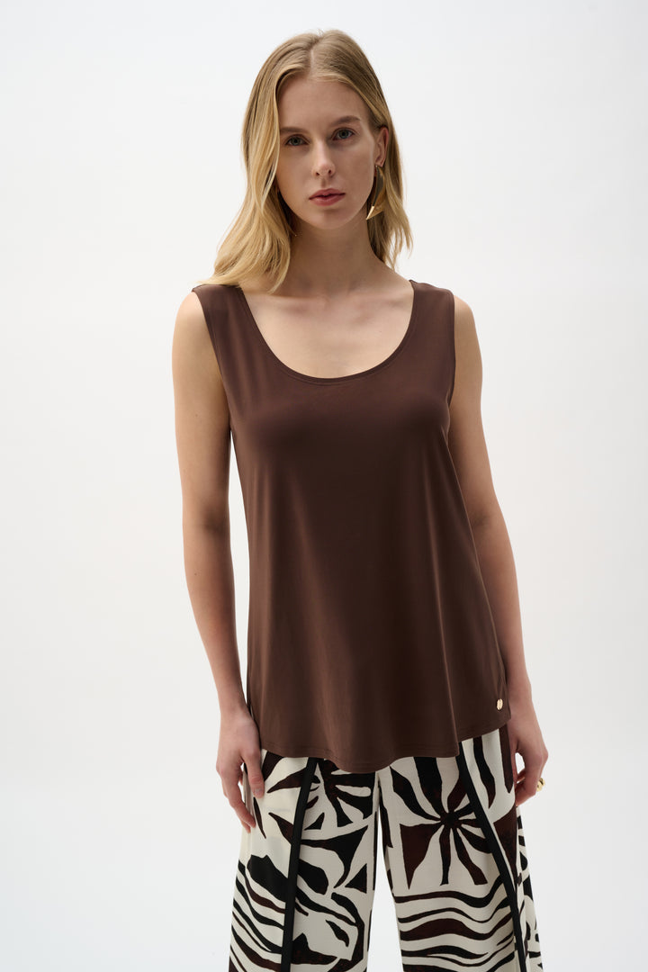 Woman wearing a brown sleeveless top and patterned pants on a white background