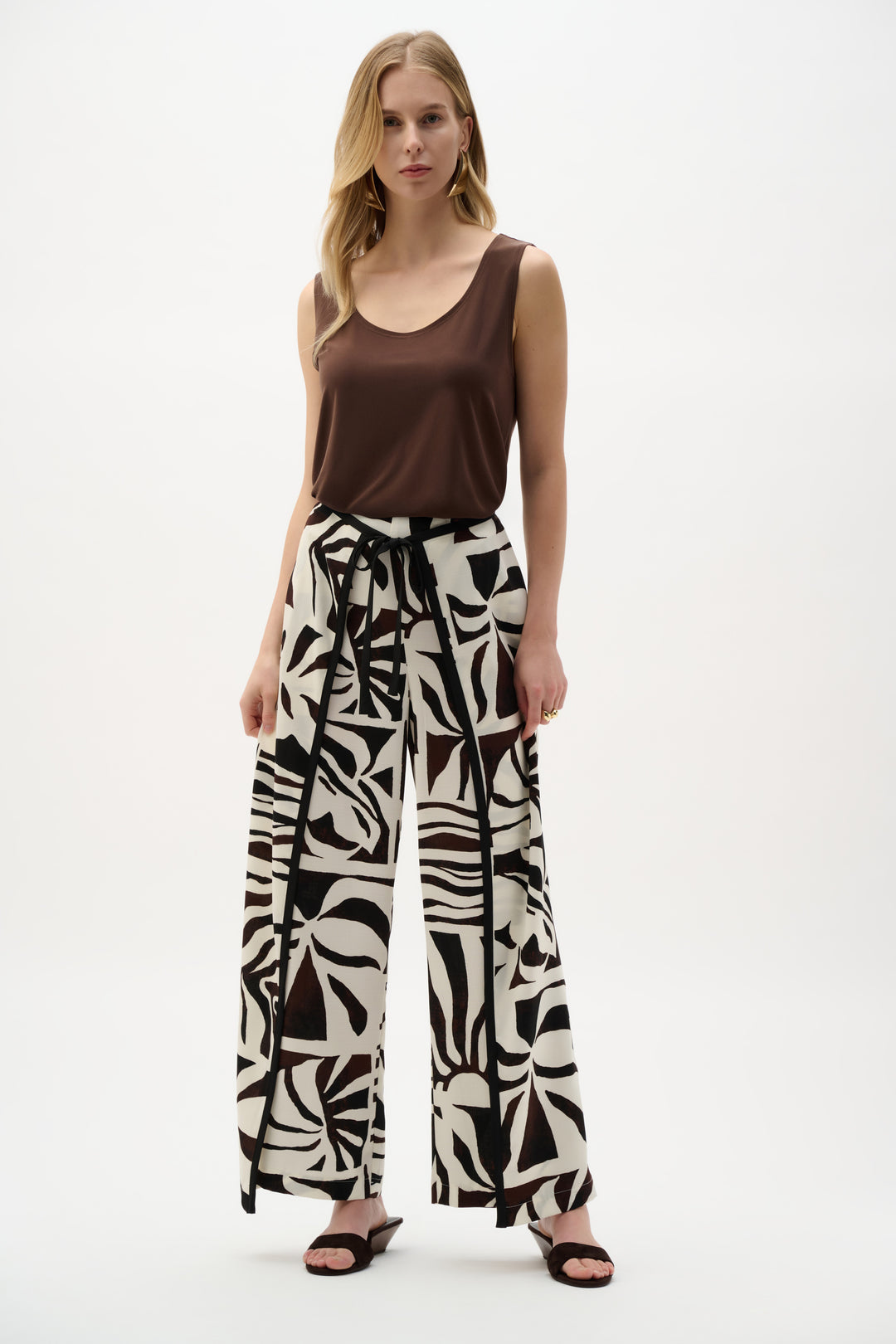 Woman wearing a brown top and patterned pants on a white background