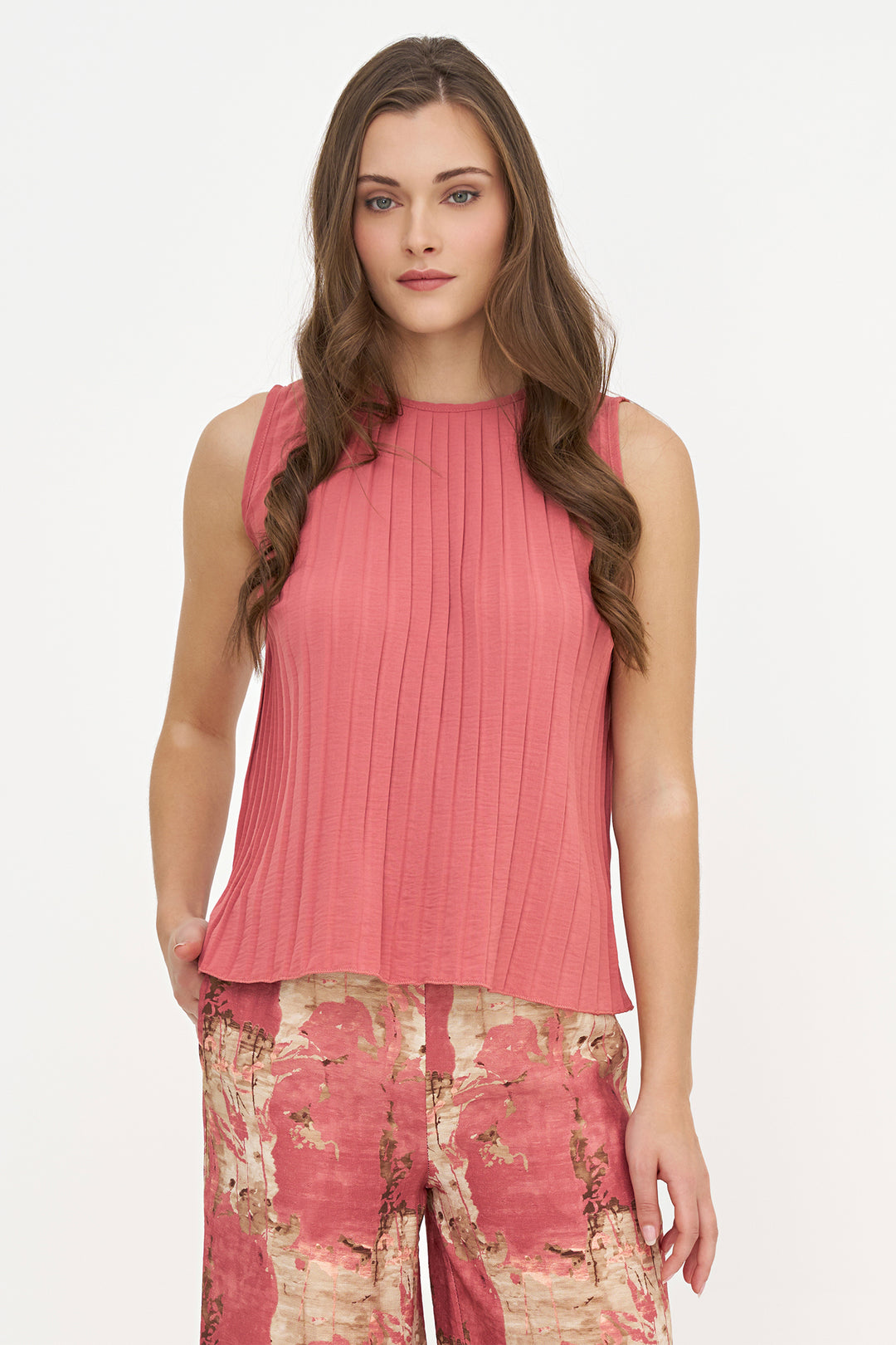 A woman modeling a sleeveless, ribbed pink top paired with pink and beige floral pants against a plain white studio background.