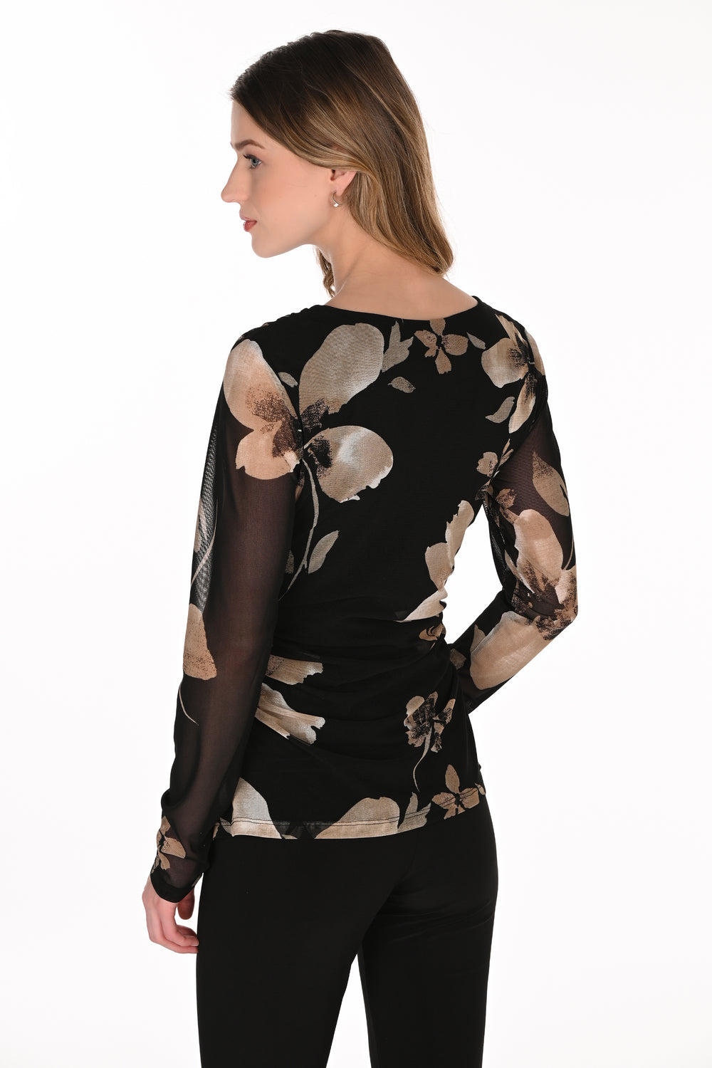 A woman shown from the back wearing a black long-sleeve top with a beige and brown floral pattern and sheer sleeves, paired with black pants, against a plain white background.
