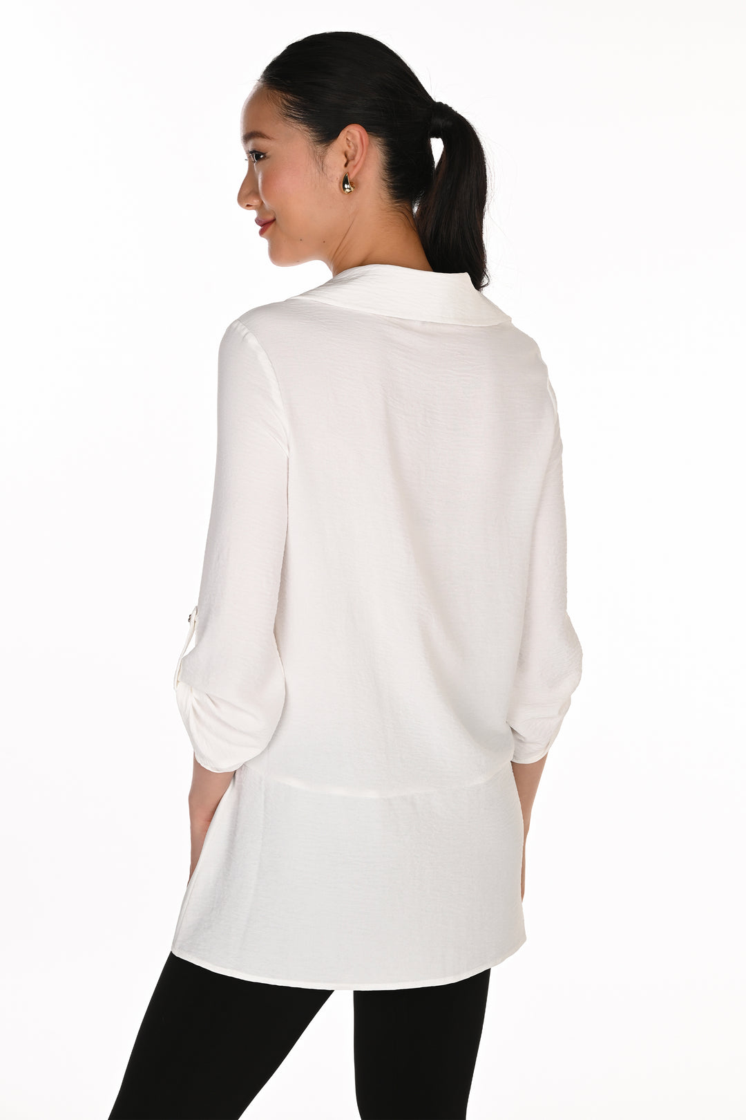 A woman shown from the back wearing a white long-sleeve collared blouse with black pants, photographed against a plain white studio background.
