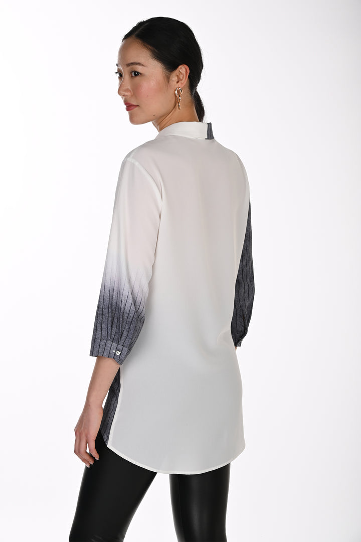 A woman shown from the back wearing a white long-sleeve tunic top with a black-to-white ombré gradient pattern on the sleeves, paired with black pants, against a plain white studio background.