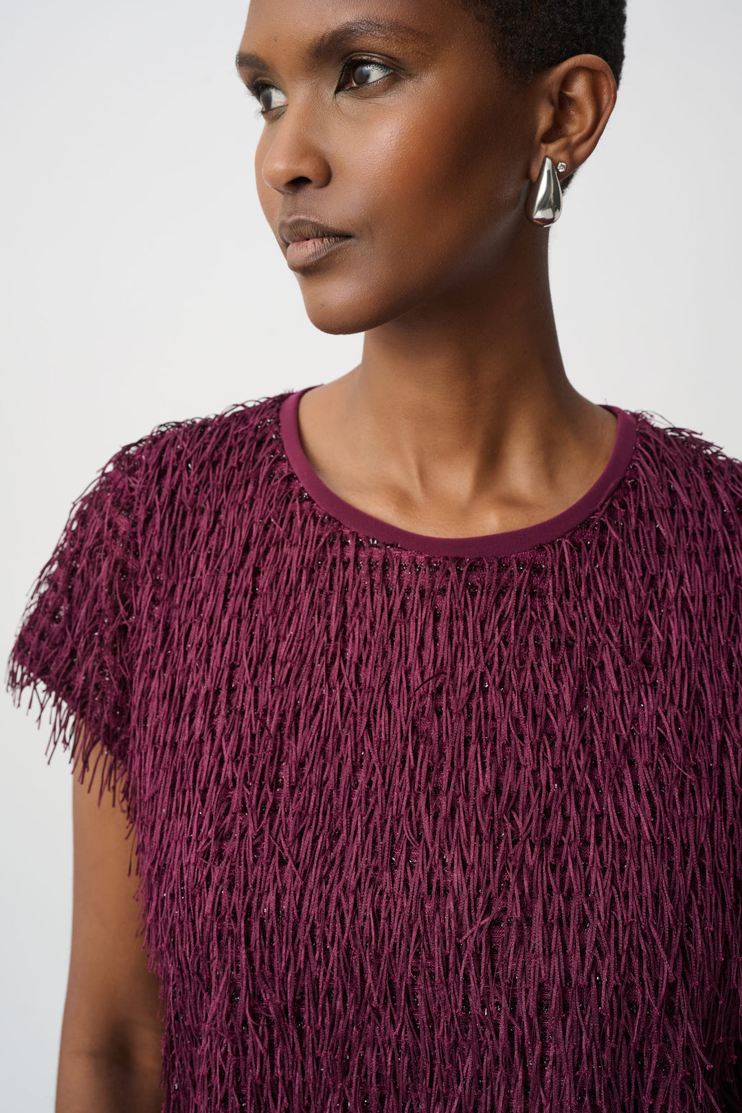 Woman wearing a purple textured top against a plain background