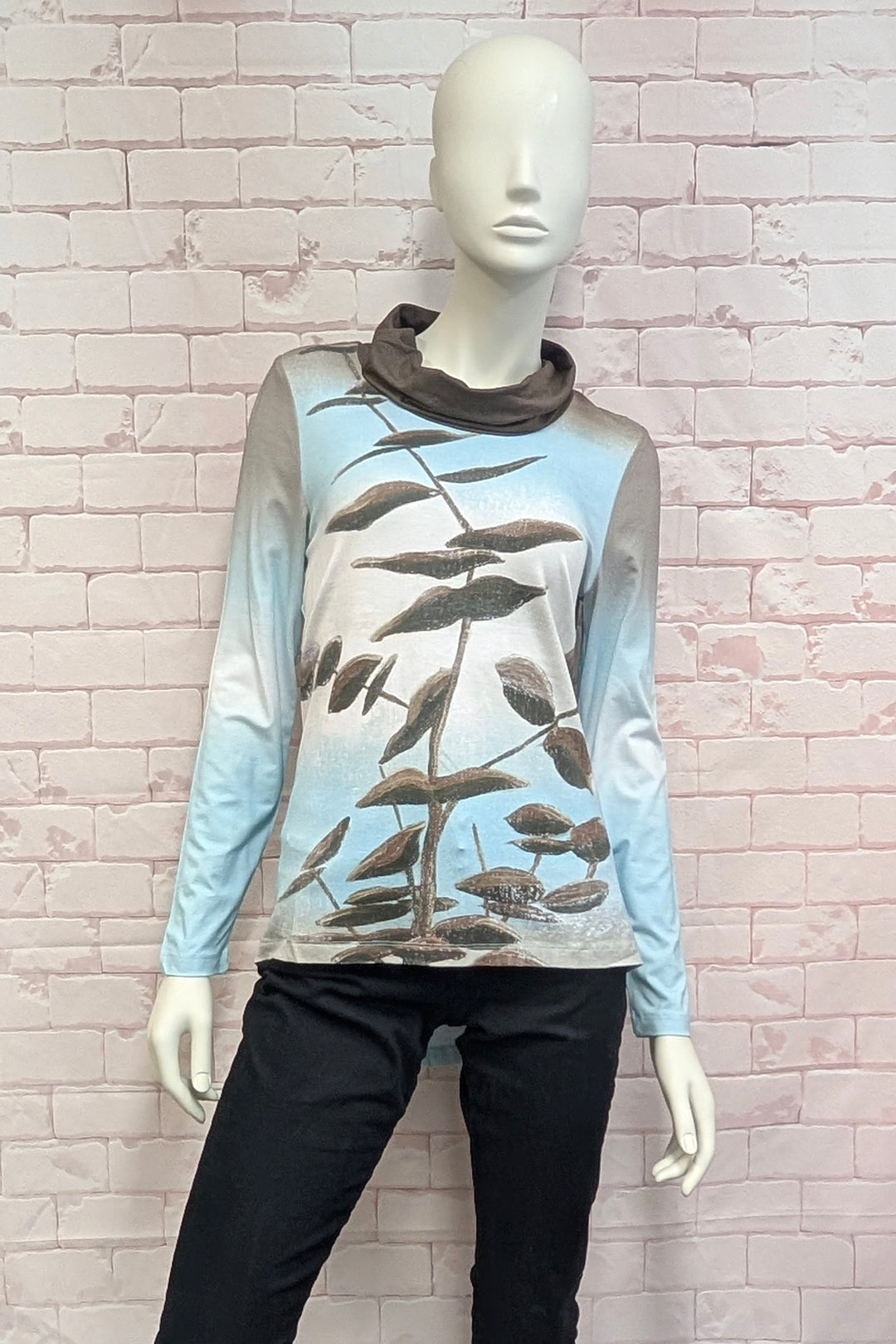 A mannequin wearing a high-low tunic blouse with blue and brown print on a white background. 