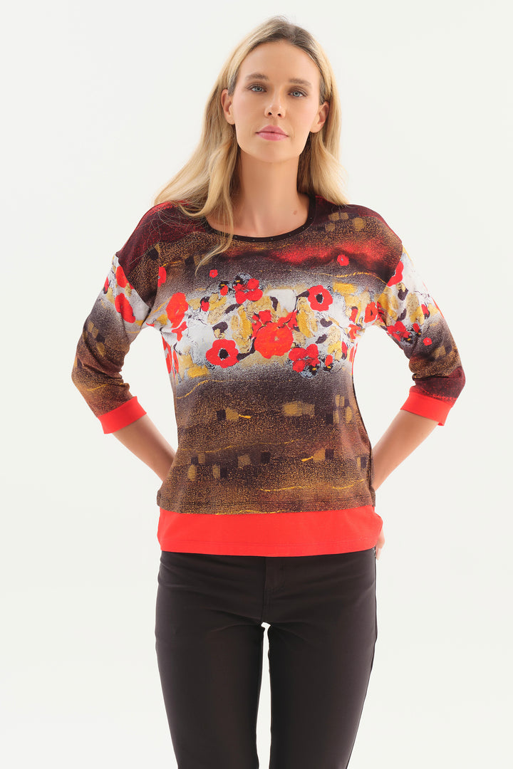 A woman modelling a red and brown printed top in front of a white background. 