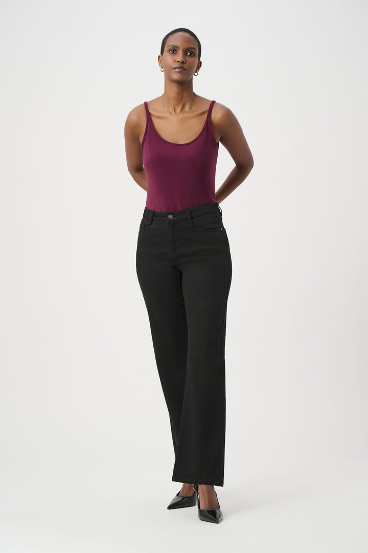 A woman modelling a purple coloured basic thin strapped camisole wearing black pants and shoes in front of a white background. 