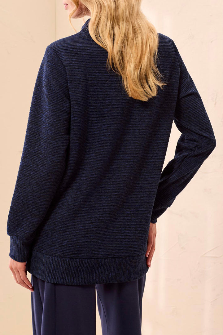 A woman shown from the back wearing a dark navy ribbed knit sweater and matching navy pants against a light beige background.
