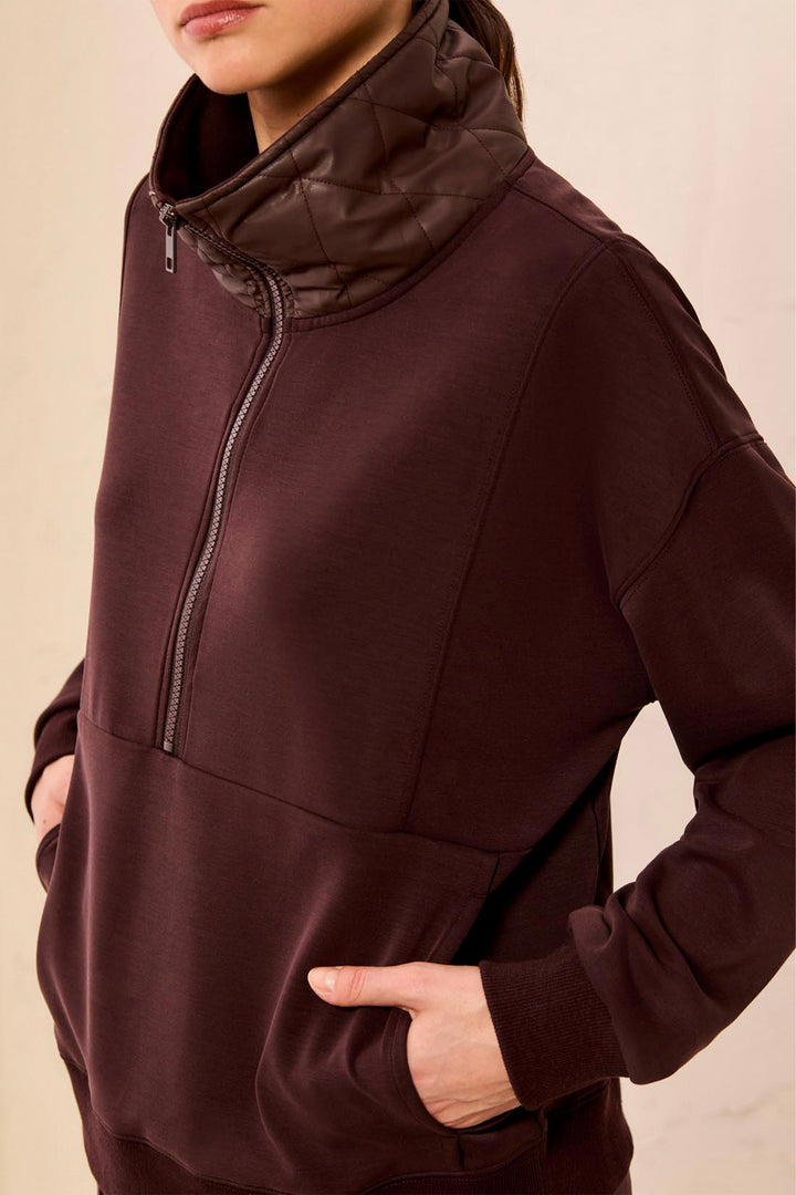 Brown zip-up sweatshirt worn by a person on a beige background