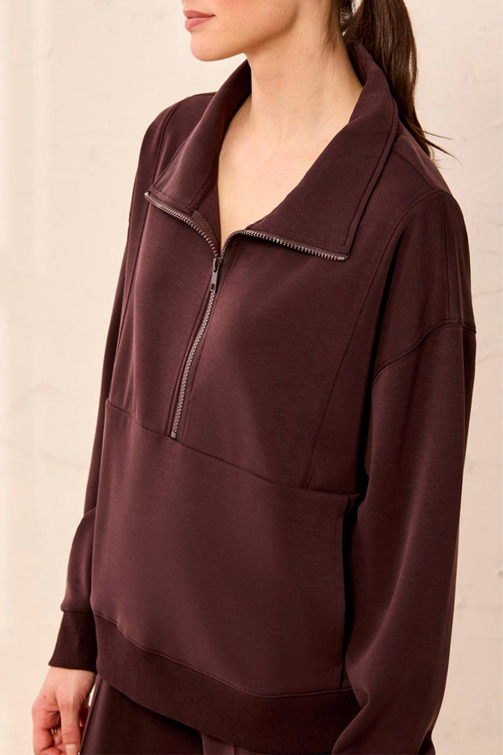 Brown zip-up sweatshirt worn by a person on a beige background