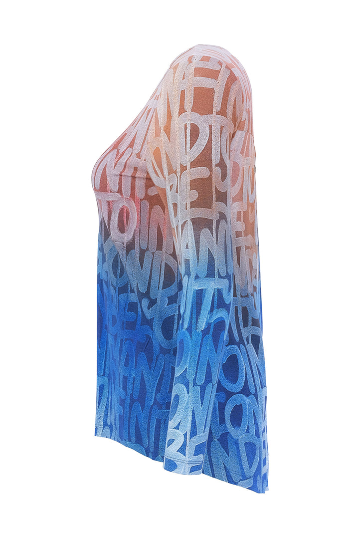 A top with an ombré gradient transitioning from peach-pink at the top to light blue and dark blue at the bottom, covered in a white graffiti-style text pattern, shown on a white background.