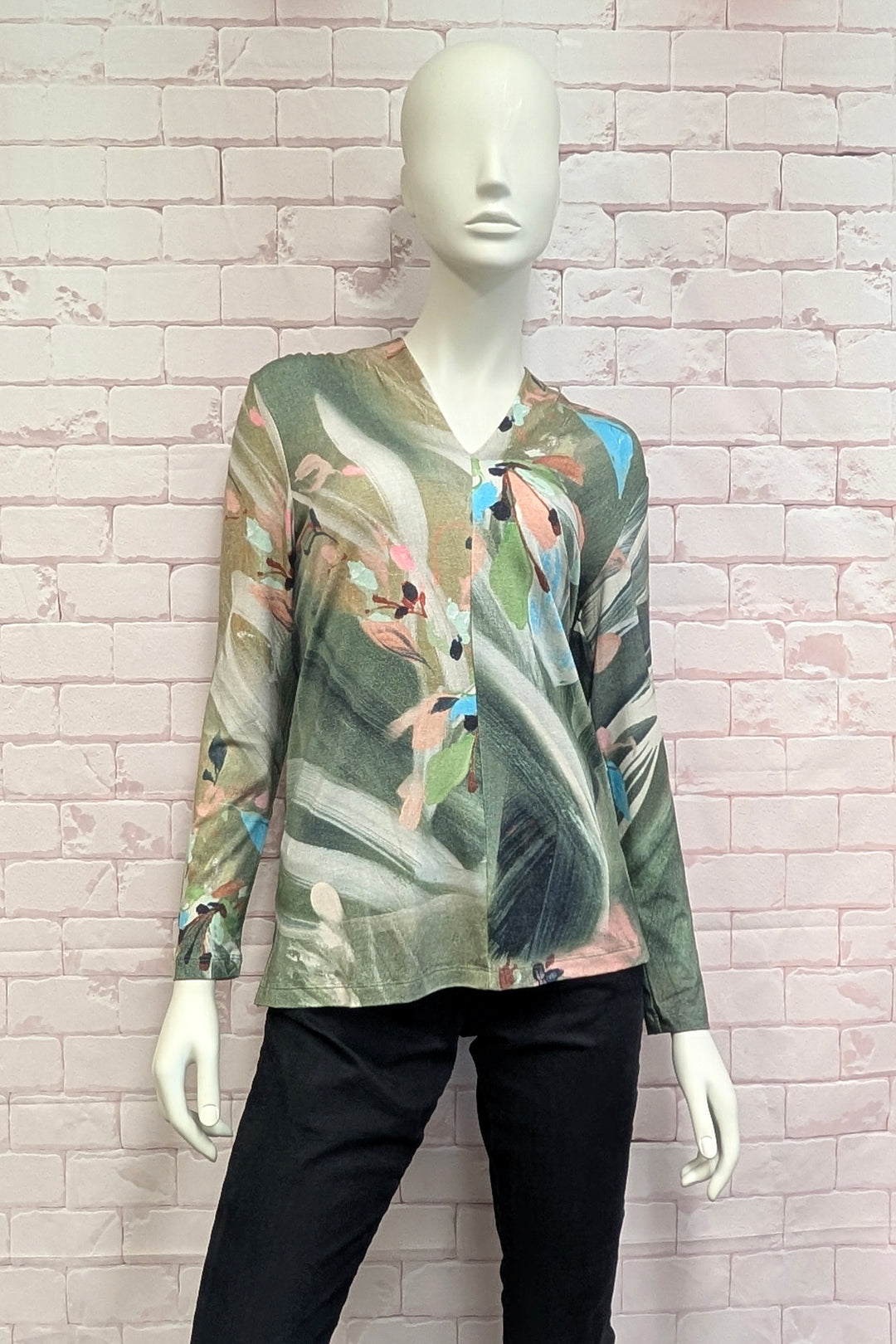 A mannequin wearing a women's long-sleeve V-neck blouse with an abstract painterly print in muted green, beige, white, pink, and light blue tones. 
