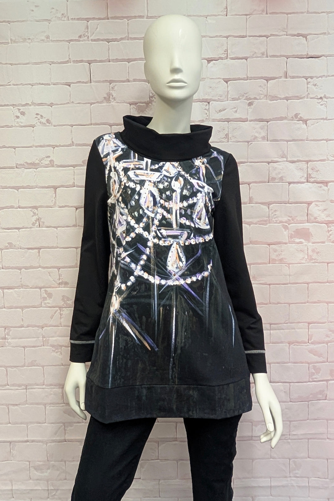 A women's mannequin wearing a long-sleeve mock neck dress in black, featuring a large white and silver graphic print of chandeliers and crystals across the front.