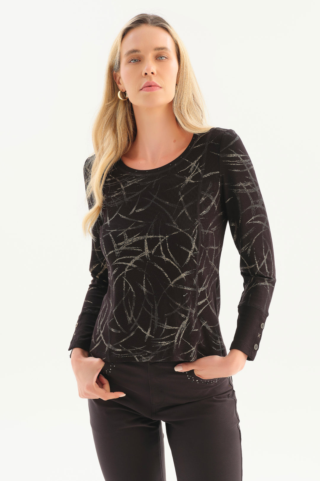 A woman modelling a black patterned top in front of a white background.