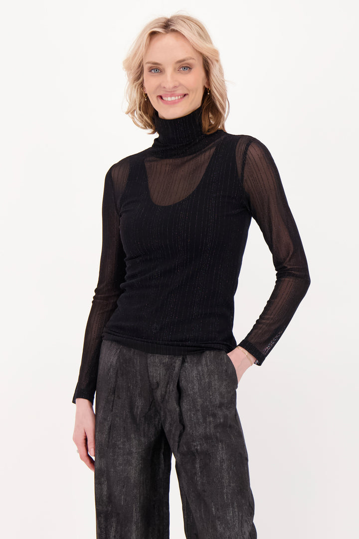 A woman modelling a sheer black long sleeve top and pants in front of a white background. 