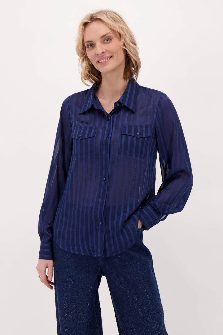 A woman modelling a navy blouse and pants in front of a white background. 