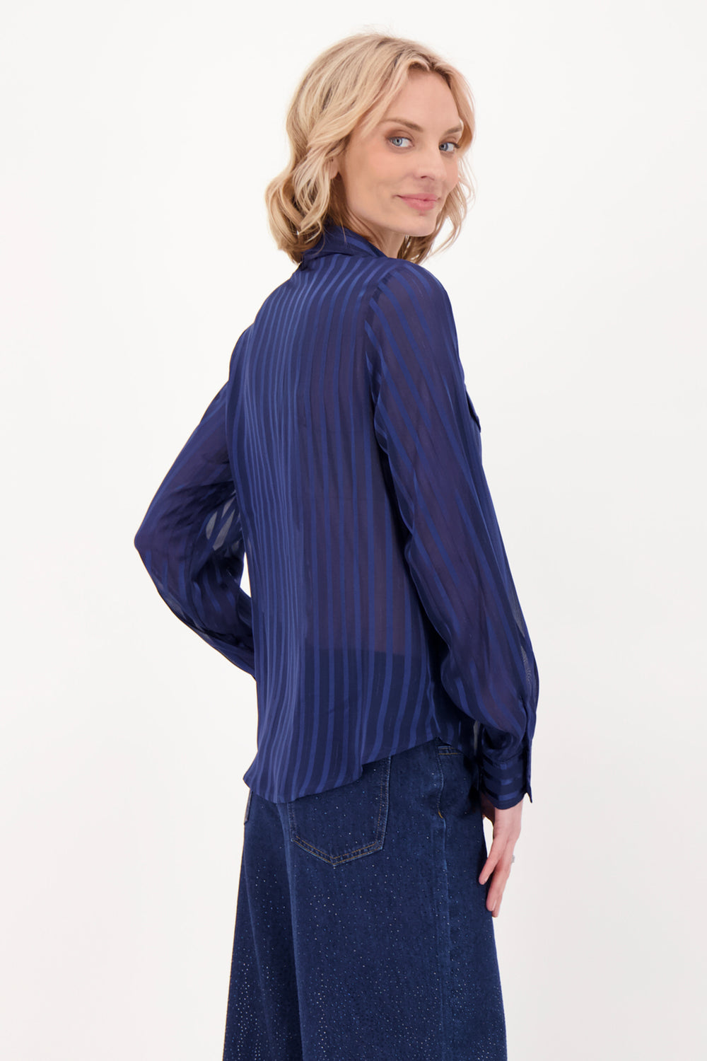 A woman modelling a navy blouse and pants in front of a white background. 