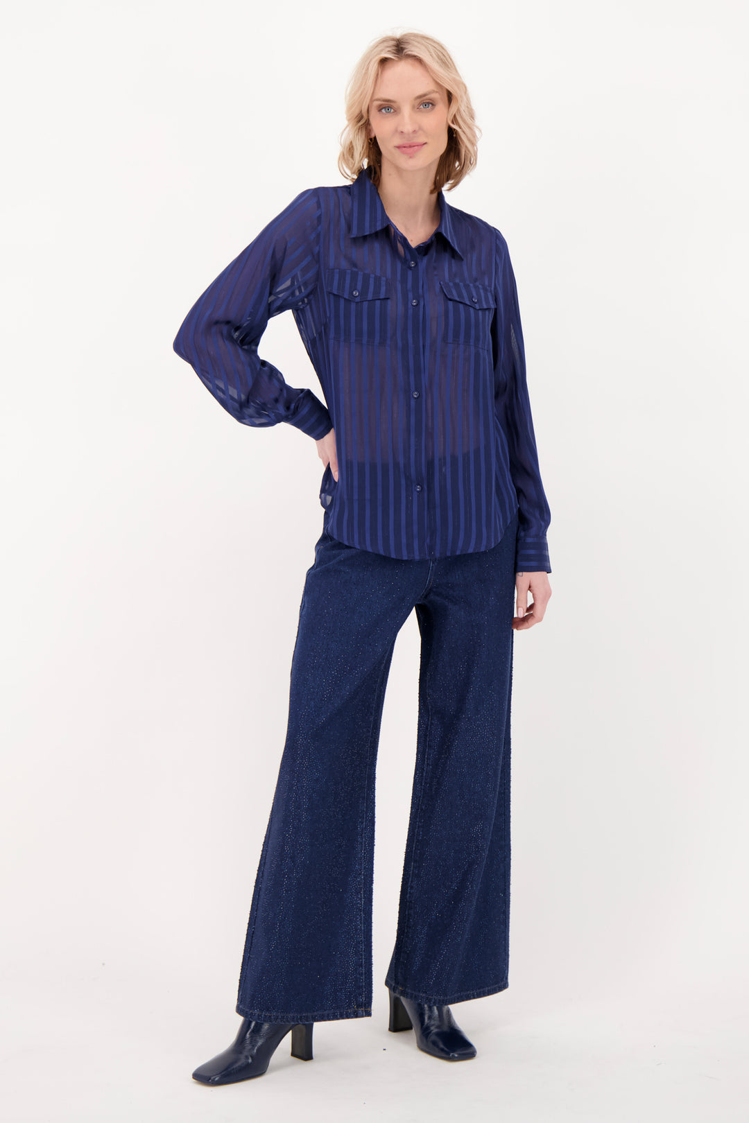A woman modelling a navy blouse and pants in front of a white background. 