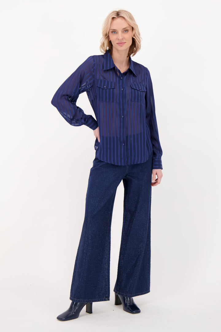 A woman modelling a navy blouse and pants in front of a white background. 