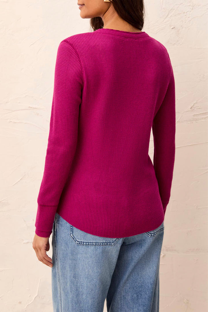 A woman shown from the back modelling a long sleeve waffle henley t-shirt standing in front of a beige background. 