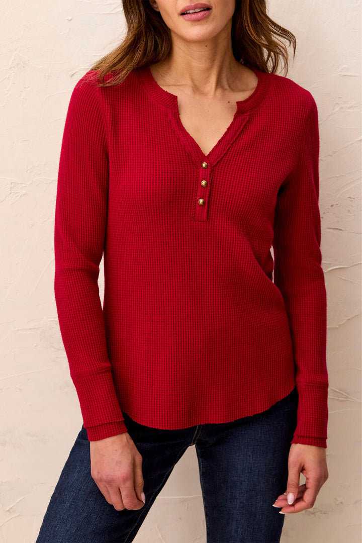 A woman modelling a long sleeve waffle henley t-shirt standing in front of a beige background. 