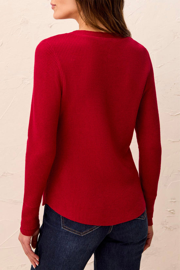 A woman shown from the back modelling a long sleeve waffle henley t-shirt standing in front of a beige background. 