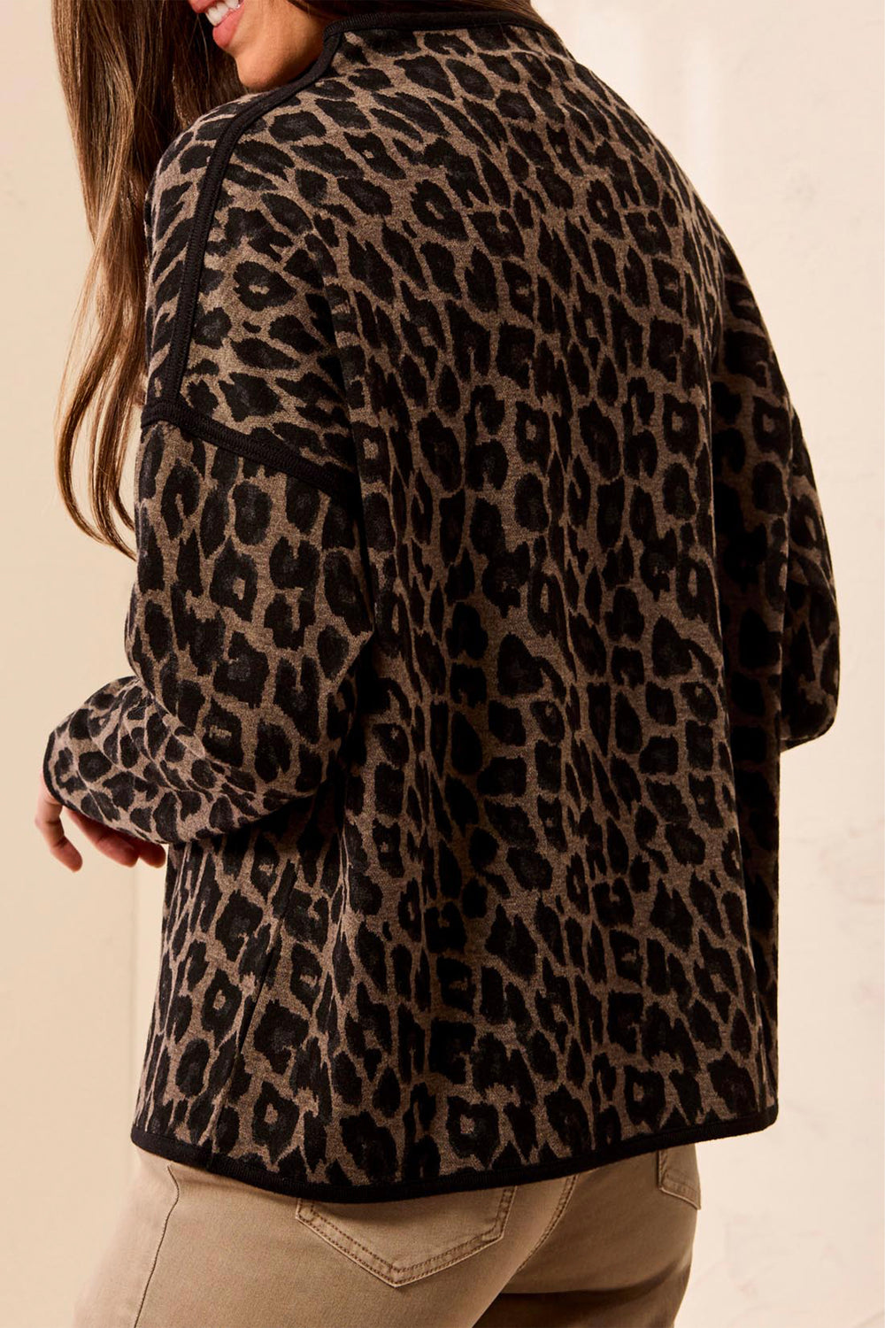 A woman shown from the back wearing a boxy animal print long sleeve sweater. 