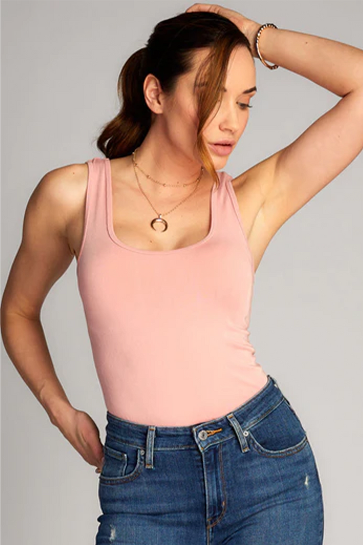 Woman wearing a blush pink tank top on white background