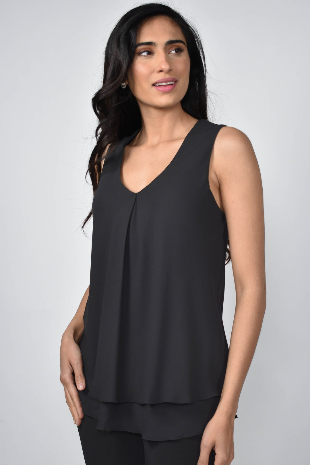 Women wearing a sleeveless layered blouse in front of grey background