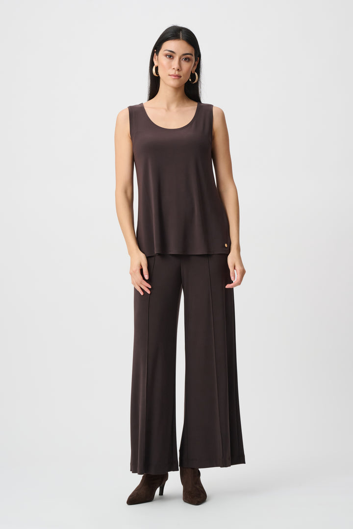 Woman wearing a brown sleeveless top and wide-leg pants on a white background
