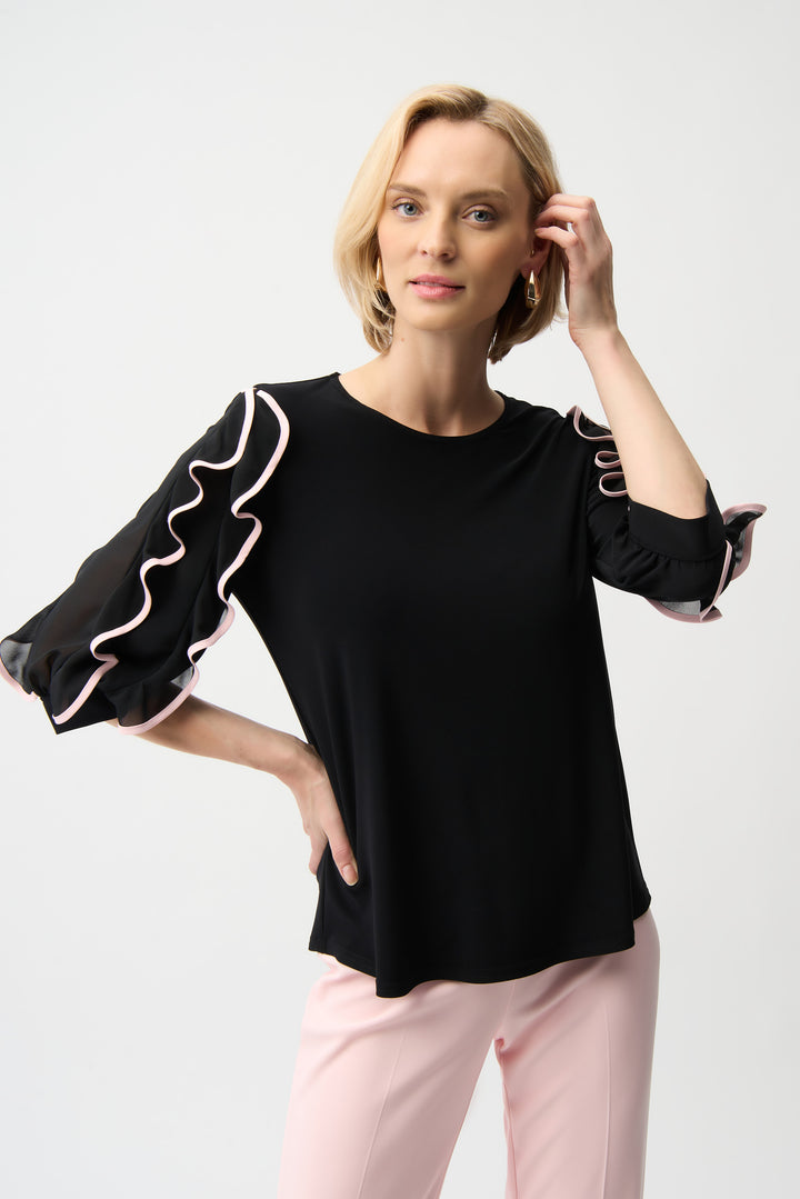 Woman wearing a black pullover top with ruffled sleeves on a white background